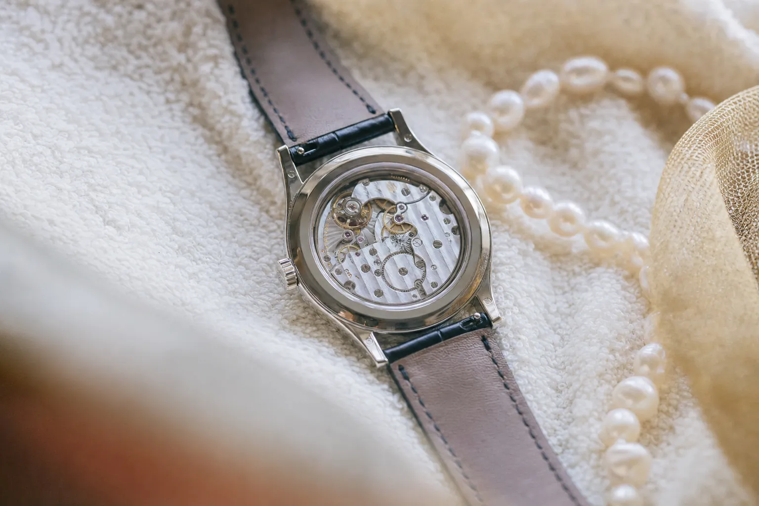 Patek Philippe Calatrava 5196G dress watch with white gold case and silver dial, movement visible through sapphire caseback, showcasing Geneva Seal craftsmanship.