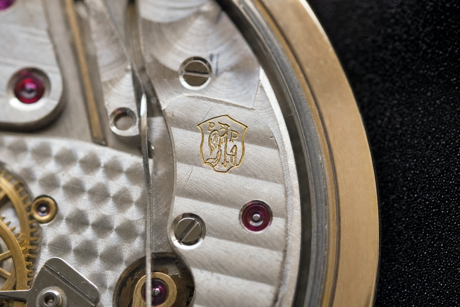 Detailed view of a vintage Patek Philippe movement, highlighting the precise engraving of the Geneva Seal hallmark and traditional horological finishing on the bridges.
