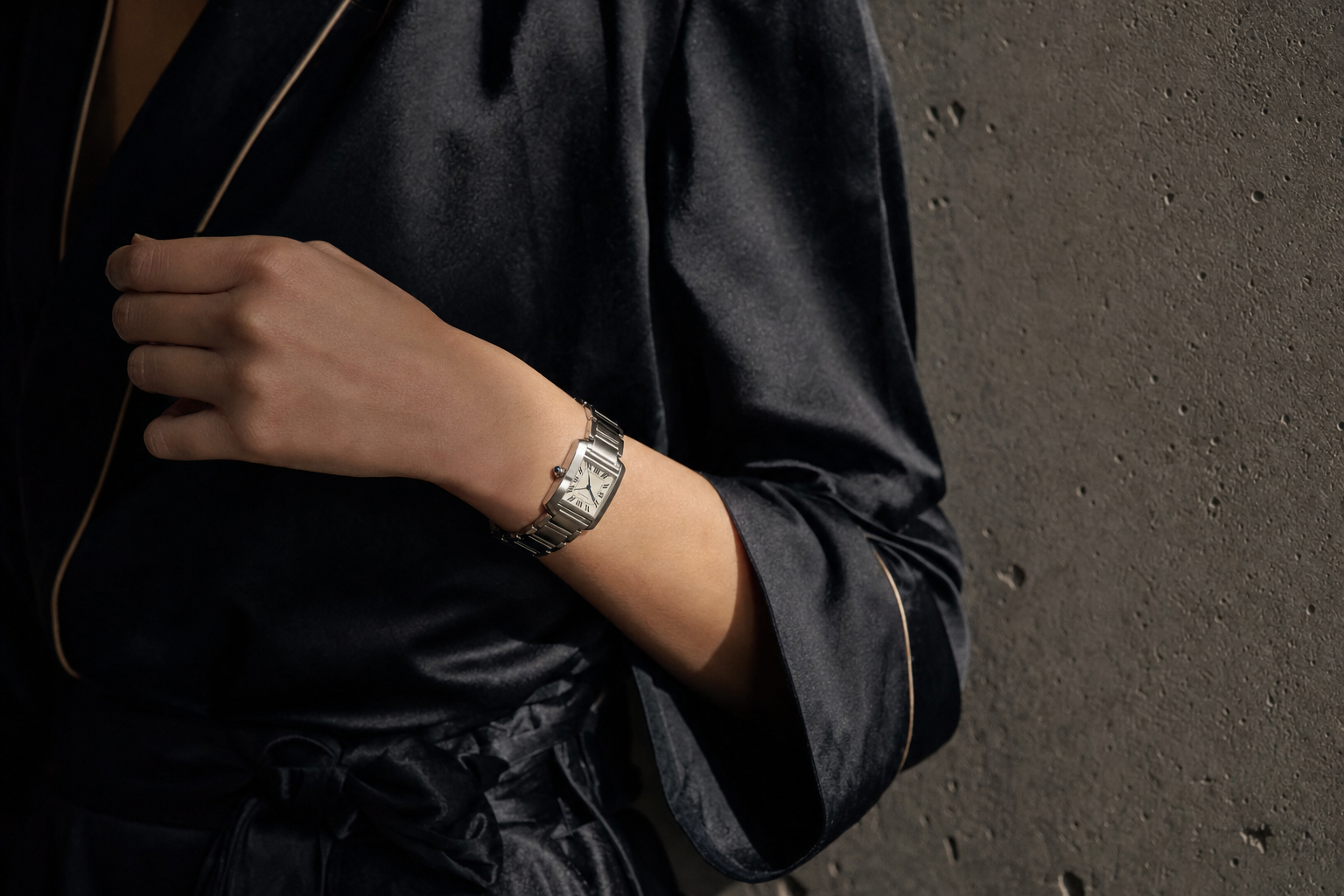 Woman wearing a classic stainless steel Cartier Tank Française watch with elegant attire, showcasing timeless luxury.
